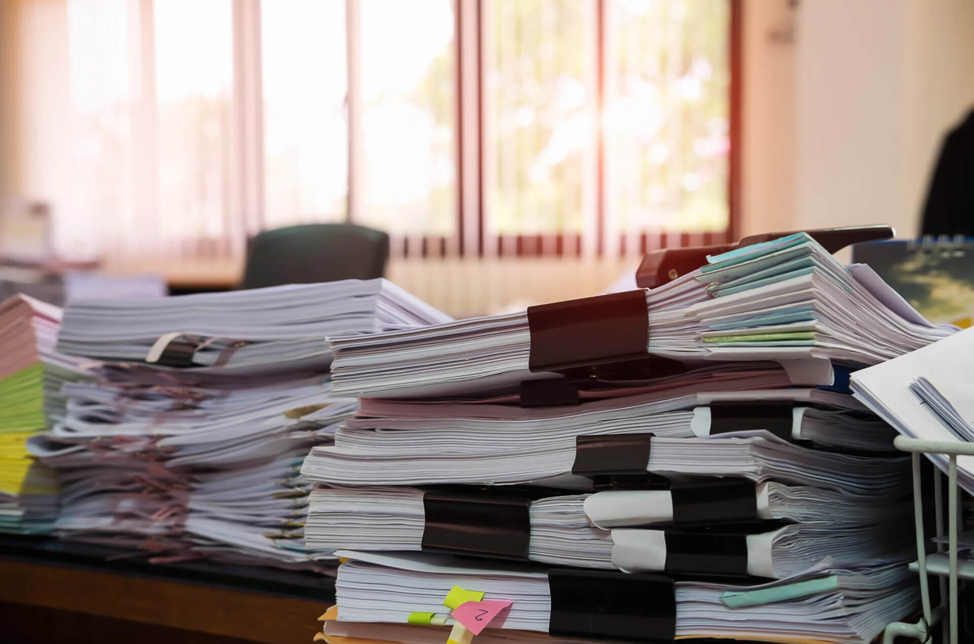 Stos papierowych list obecności na budowie – tradycyjna dokumentacja powodująca błędy i opóźnienia